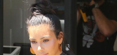 Kim Kardashian z kokiem na głowie i w szarej sukience 