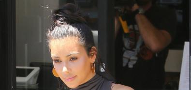 Kim Kardashian z kokiem na głowie i w szarej sukience 